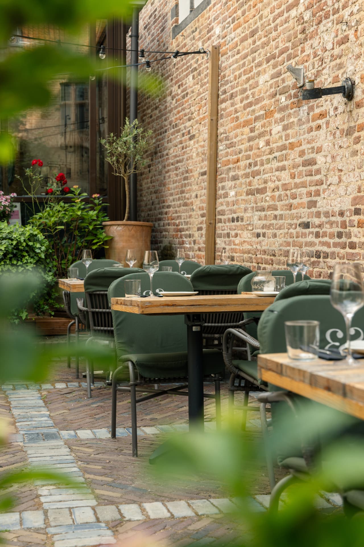 Binnentuin van Ensemble Gastro & Bar in Zwolle met houten tafels en groene stoelen